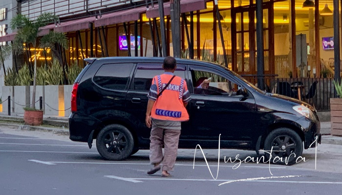 Salah seorang juru parkir di Kota Gorontalo saat menerima pembayaran dari pengunjung di sekitar pertokoan Kota Gorontalo. [foto: fikar/nusantara1]