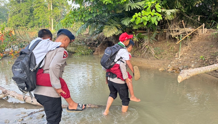 Personel Batalyon C Pelopor Satbrimob Polda Gorontalo saat membantu anak sekolah menyeberang sungai [foto:dok/humas]