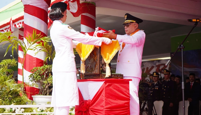 Bupati Gorontalo, Sofyan Puhi saat menyerahkan bendera Merah Putih kepada Paskibraka untuk dikibarkan pada upacara HUT Proklamasi. [foto:dok/kominfo]
