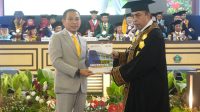 Sekretaris Komisi IV DPRD Provinsi Gorontalo, Moh. Abd. Ghalieb I. Lahidjun saat menerima menerima Buku Alumni dari Rektor UNIGO, Robby Hunawa. [foto:dok/ist]