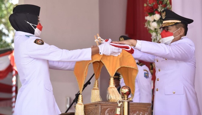 Penjagub Gorontalo, Hamka Hendra Noer ketika menyerahkan Bendera Merah Putih kepada tim Paskibraka pada peringatan HUT ke-77 RI di halaman Rujab Gubernur, Rabu (17/8/2022). (Foto : Ist/Diskominfotik)