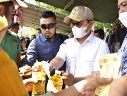 Penjagub Gorontalo, Hamka Hendra Noer saat melayani langsung masyarakat yang membeli pada bahan pokok di pasar murah yang digelar oleh Dinas Koperasi UMKM Perindustrian dan Perdagangan Provinsi Gorontalo, Ahad (7/11/2022) di Lapangan Taruna Remaja. (Foto:Ist/Diskominfotik)