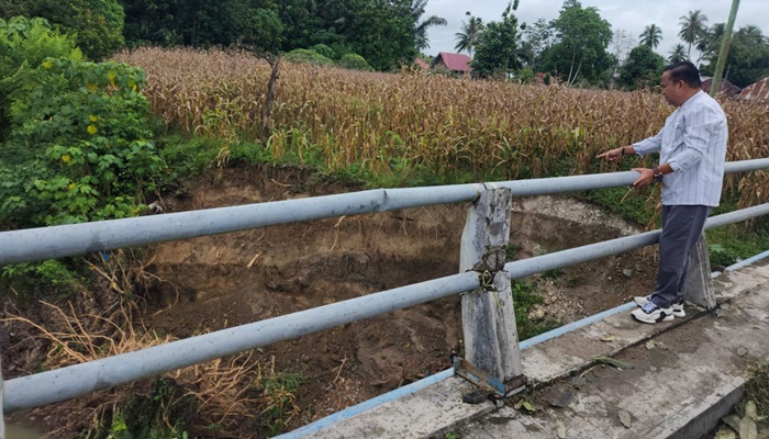 Anggota DPRD Kabupaten Gorontalo, Aleg Ali Polapa saat meninjau lokasi jembatan yang sudah tergerus pinggirannya dan butuh penangan yang lebih. (Foto: Ist)