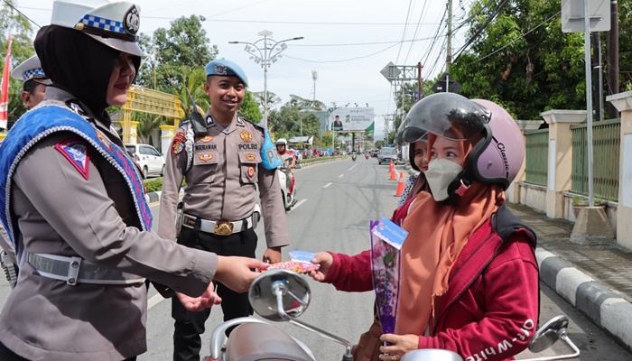 Petugas dari Satlantas Polresta Gorontalo Kota saat menyerahkan bunga dan coklat kepada pengendara yang tertib lalu lintas di momen Hari Valentin. (Foto: Ist)