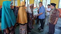 Wakil Bupati Gorontalo, Hendra Hemeto saat menyerahkan bantuan beras kepada warga Desa Tinelo. [Foto:Ist]