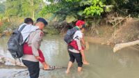 Personel Batalyon C Pelopor Satbrimob Polda Gorontalo saat membantu anak sekolah menyeberang sungai [foto:dok/humas]