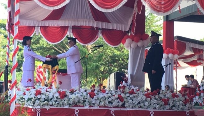 Bupati Bone Bolango, Ismet Mile saat menyerahkan bendera Merah Putih kepada Paskibraka untuk dikibarkan pada upacara HUT ke-81 Kemerdekaan RI di Lapangan Alun-Alun Bone Bolango, Senin 17 Agustus 2026. [foto:dok/indra/diskominfo]